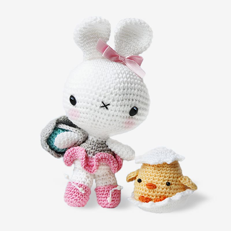 Amigurumi bunny and chick, bunny wearing crocheted basket with eggs, chick sitting in a broken eggshell.