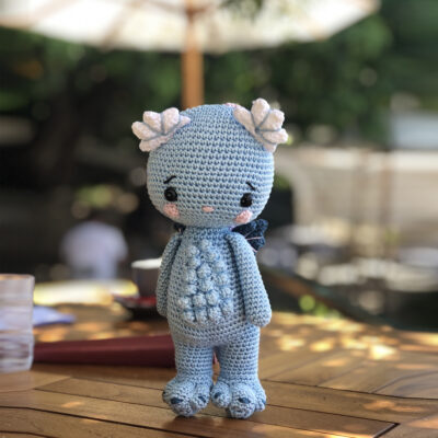 Amigurumi lady dragon seeking some shade on a sunny day under the parasol.