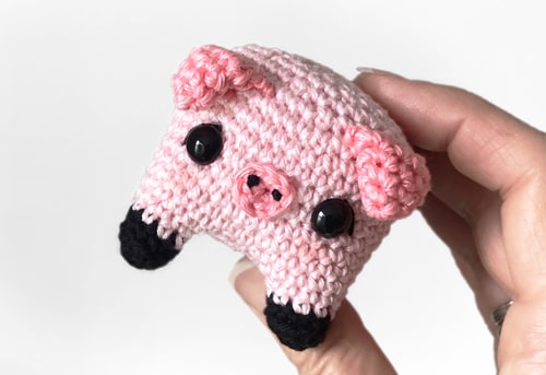 Cute little amigurumi pig held in hand