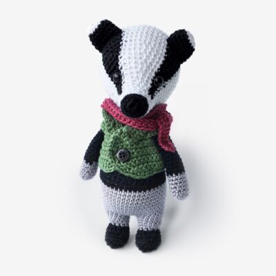 Crochet badger wearing red scarf and green sweater.