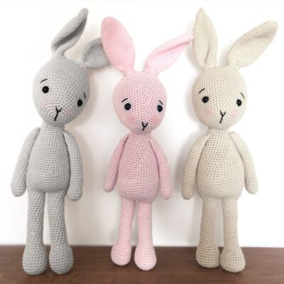 Grey, pink and cream crochet bunny rabbits, standing next to each other