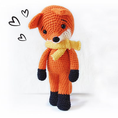 Amigurumi crochet fox, wearing yellow knitted scarf. Heart illustrations are around its head.