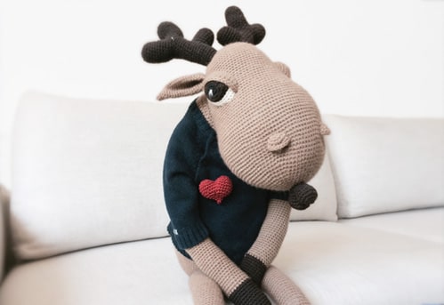 Amigurumi moose wearing crochet heart pin.