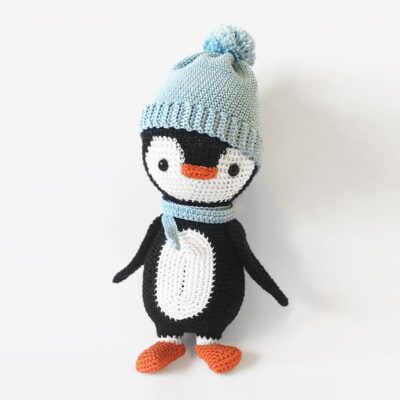 Crochet penguin wearing blue hat and scarf.