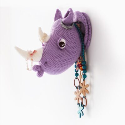 Crochet rhino head wall mount, faux taxidermy. Rhino head hanging on the wall with necklaces and braceletes hanging around the neck and the horn.