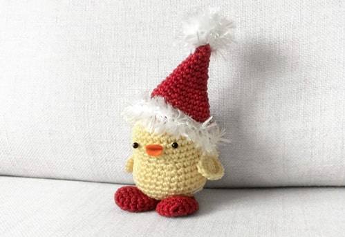 Crochet baby chicken with Santa's hat on the head.