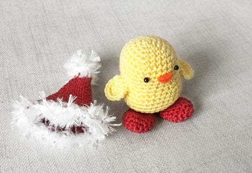 Crochet chick and Santa's hat laying beside.