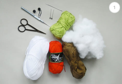 Materials needed to crochet amigurumi owl, such as yarn in green, orange, brown and white, scissors, crochet hook, soft stuffing, plastic eyes, sewing pins and a tapestry needle.